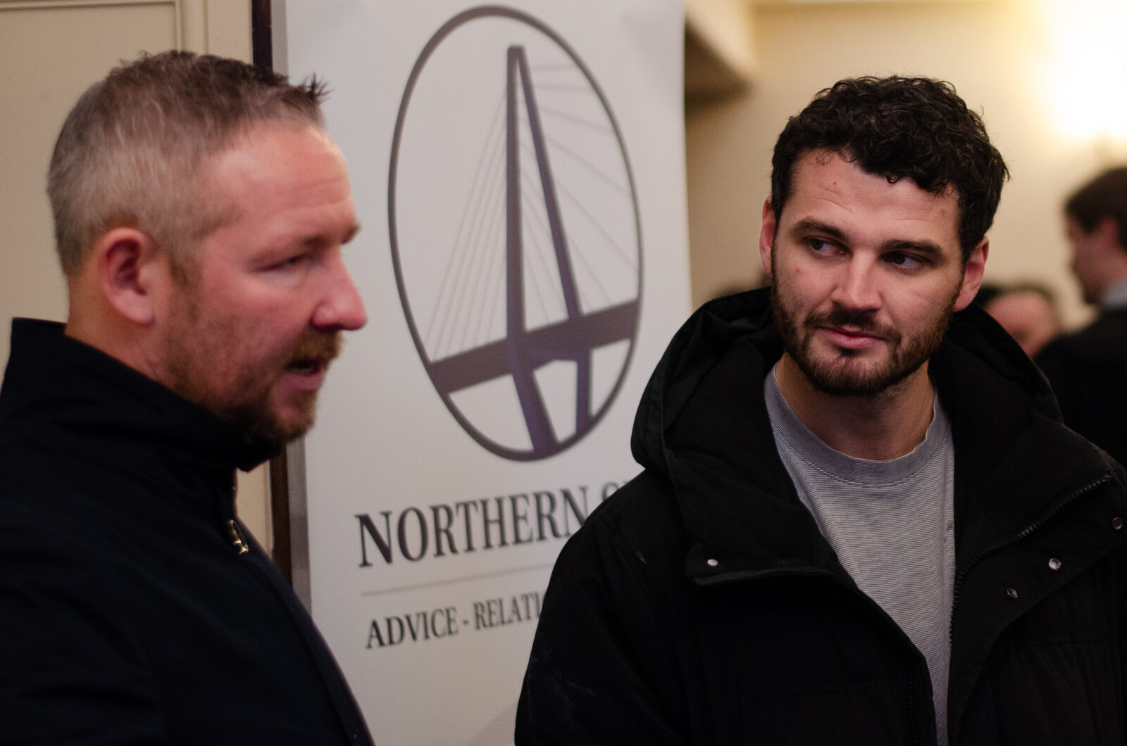 Guests networking beside the Northern Spire banner